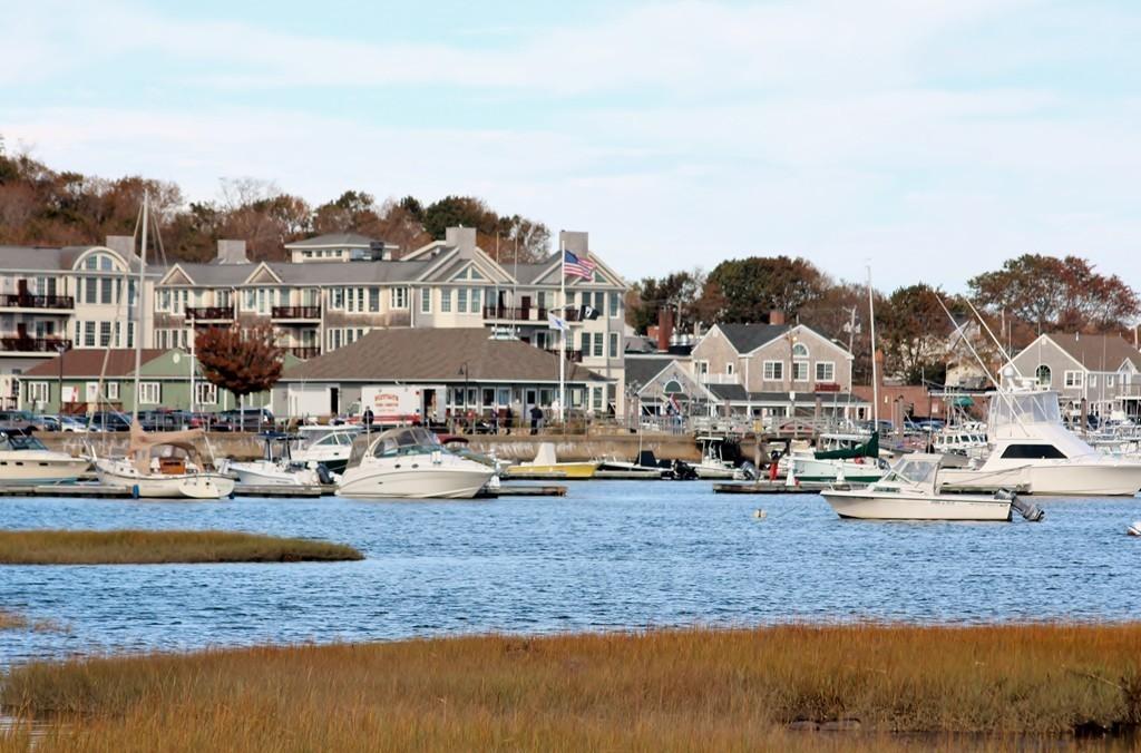 Scituate Harbor in fall, with moored boats, marsh grass in the foreground, and waterfront buildings along Front Street